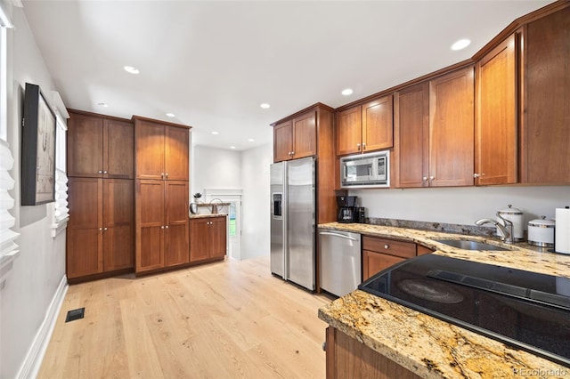 400 S Gilpin St, Denver, CO 80209 - kitchen featuring appliances with stainless steel finishes, light wood-style flooring, recessed lighting, light stone countertops, and brown cabinetry