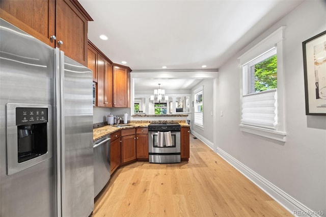 400 S Gilpin St, Denver, CO 80209 - kitchen featuring appliances with stainless steel finishes, a peninsula, light wood-type flooring, brown cabinetry, and light stone countertops