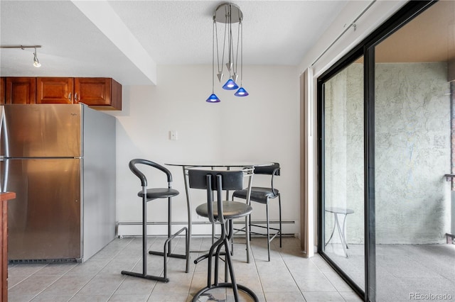 dining area with baseboard heating, a textured ceiling, a healthy amount of sunlight, and light tile patterned floors