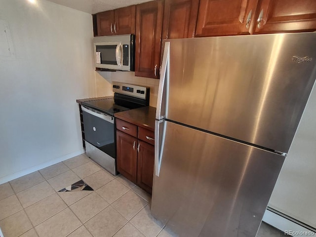 kitchen with dark countertops, tasteful backsplash, light tile patterned floors, a baseboard radiator, and stainless steel appliances