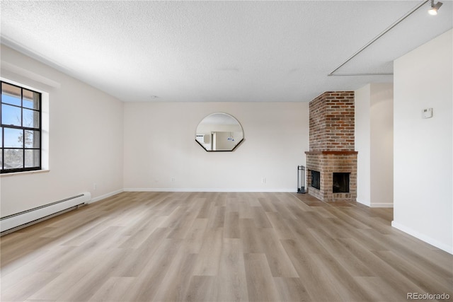unfurnished living room with light wood-style floors, a textured ceiling, baseboards, and a fireplace