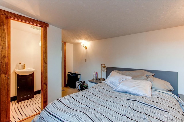 bedroom with light colored carpet, sink, and a textured ceiling