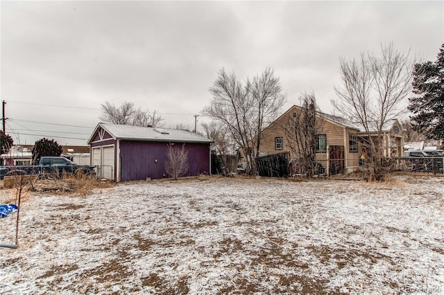 view of snowy exterior featuring an outbuilding and a garage