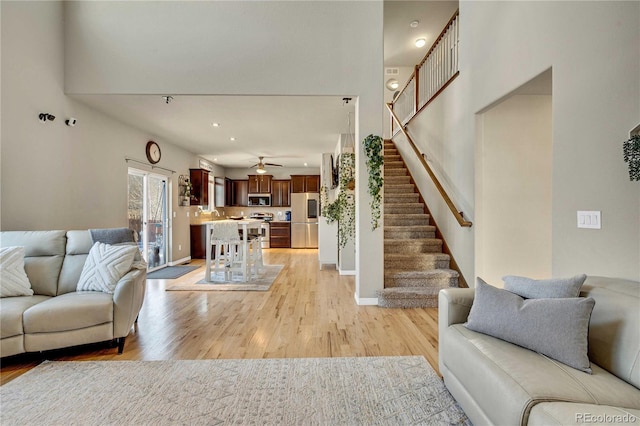 living room with a towering ceiling and light hardwood / wood-style flooring