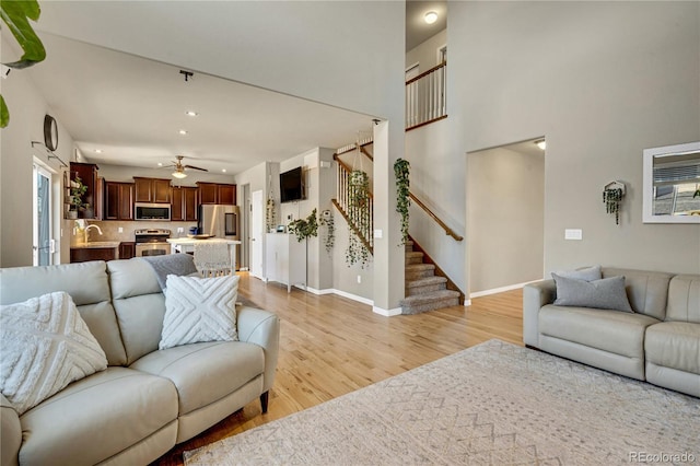 living room with ceiling fan, sink, and light wood-type flooring