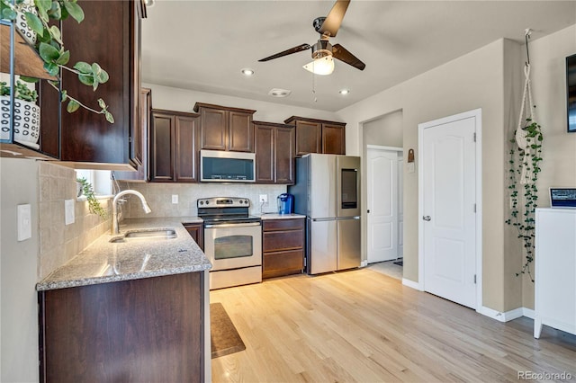 kitchen with sink, decorative backsplash, stainless steel appliances, light stone countertops, and light hardwood / wood-style flooring