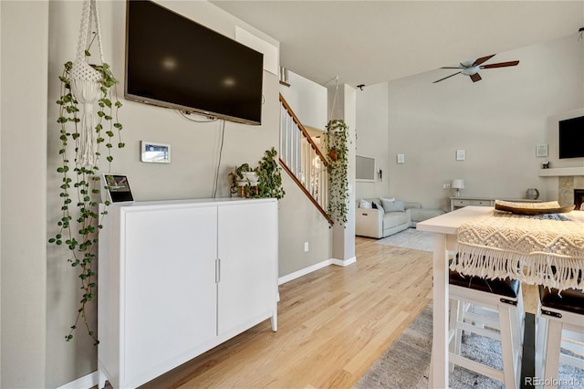 kitchen with white cabinetry, a fireplace, light hardwood / wood-style floors, and ceiling fan