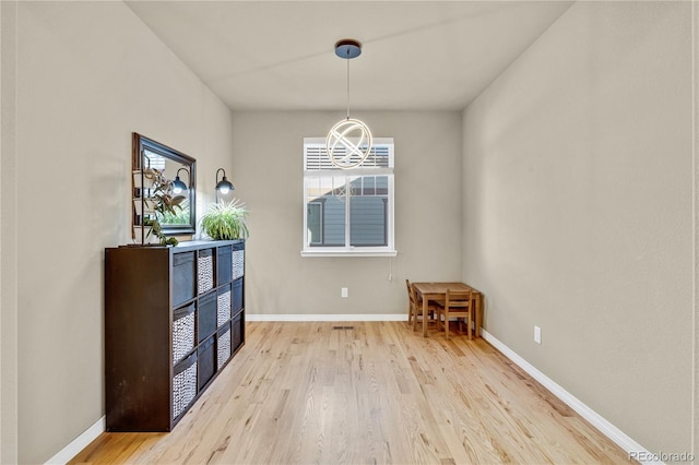 unfurnished dining area featuring a notable chandelier and light wood-type flooring