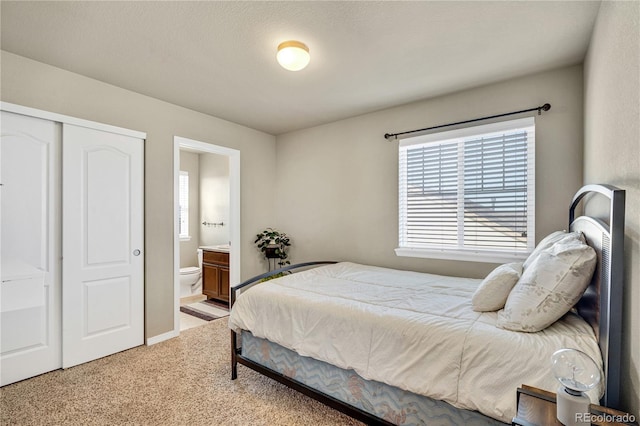 bedroom featuring light carpet, a closet, and ensuite bathroom