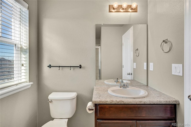 bathroom with vanity, a wealth of natural light, and toilet