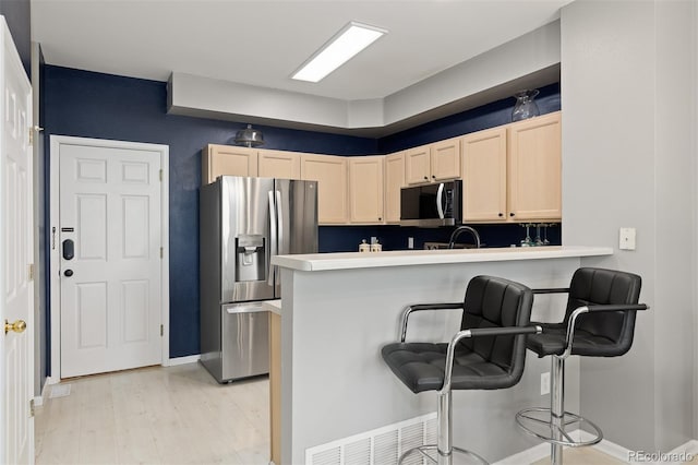 5555 E Briarwood Ave Unit 1404, Centennial, CO 80122 - kitchen featuring stainless steel refrigerator with ice dispenser, light brown cabinetry, a peninsula, a breakfast bar area, and light wood-type flooring