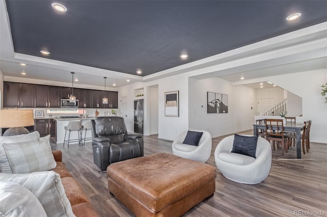 living area with stairs, a raised ceiling, recessed lighting, and dark wood-style flooring