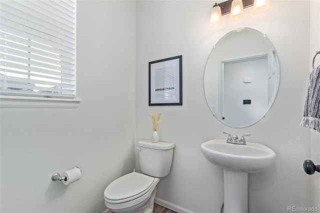 half bathroom featuring toilet, baseboards, and a sink