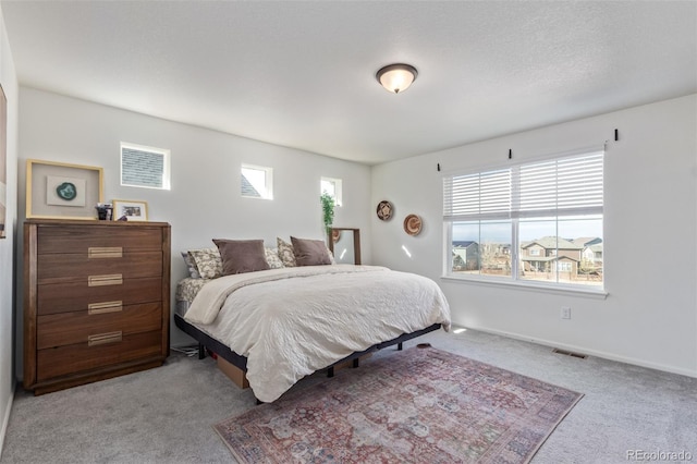 carpeted bedroom featuring visible vents, multiple windows, and baseboards