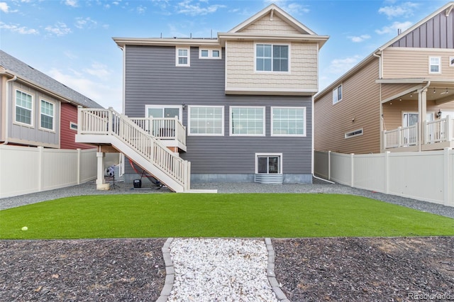 rear view of property featuring stairway, a lawn, and a fenced backyard