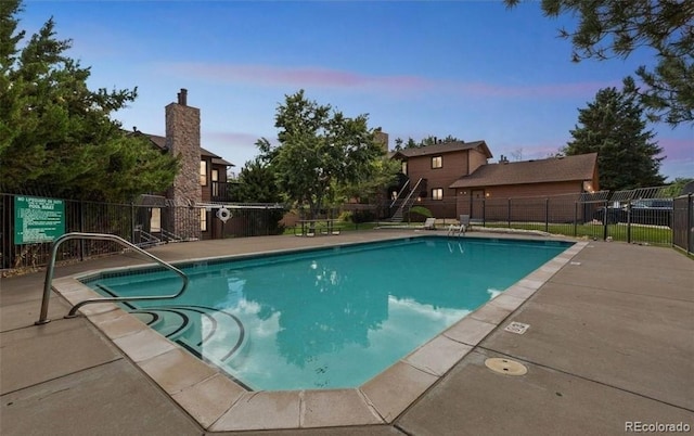 pool at dusk featuring a patio area, a community pool, and fence