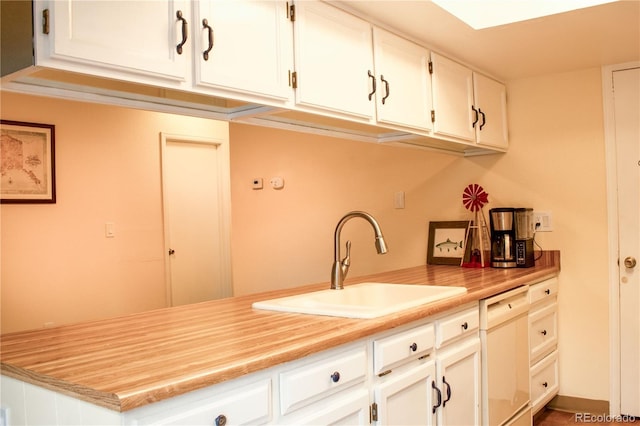 kitchen featuring a sink, dishwasher, white cabinets, and light countertops