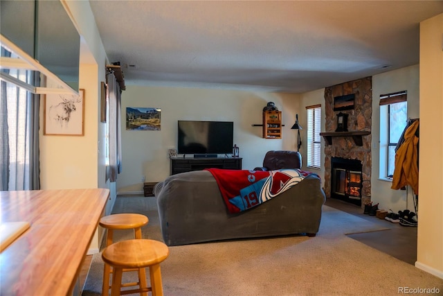 carpeted living room with a stone fireplace