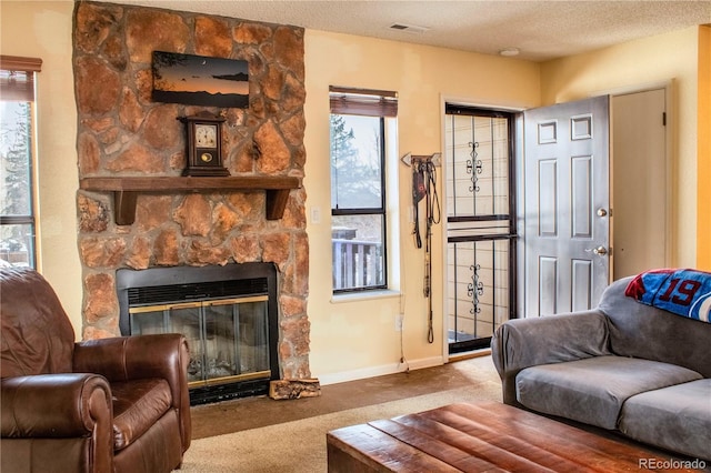 carpeted living room with a fireplace, baseboards, visible vents, and a textured ceiling