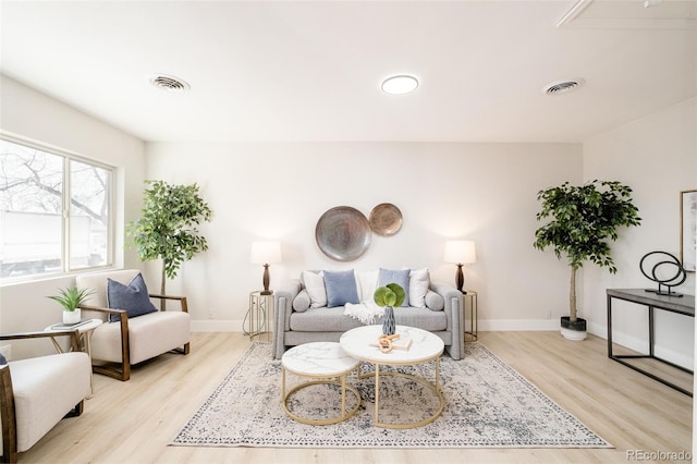 living room with light wood finished floors, baseboards, and visible vents