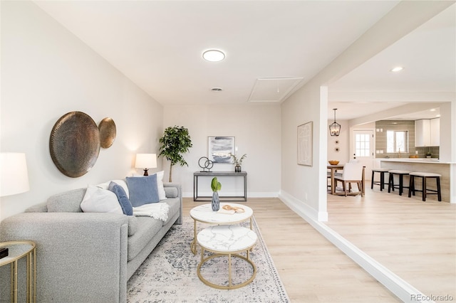 living room with baseboards, recessed lighting, attic access, and light wood-style floors