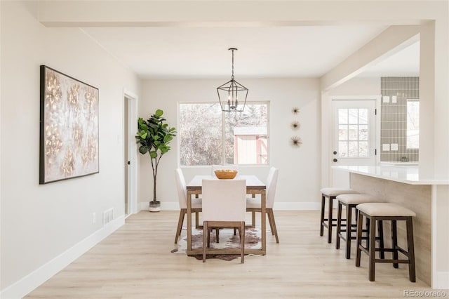 dining space with light wood-type flooring, baseboards, visible vents, and a chandelier