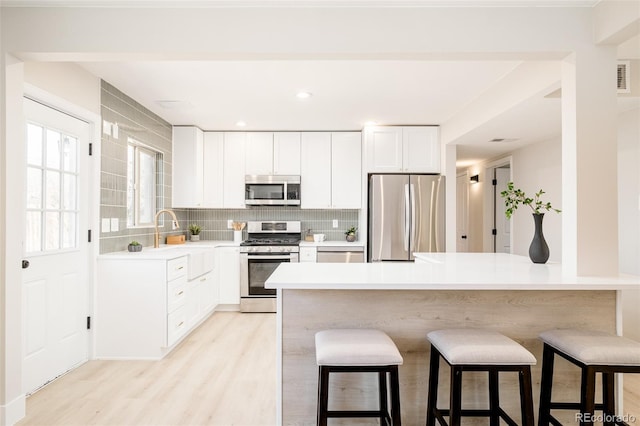 kitchen with stainless steel appliances, a breakfast bar, a sink, and tasteful backsplash