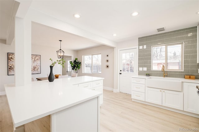 kitchen with light wood-style floors, light countertops, visible vents, and a sink