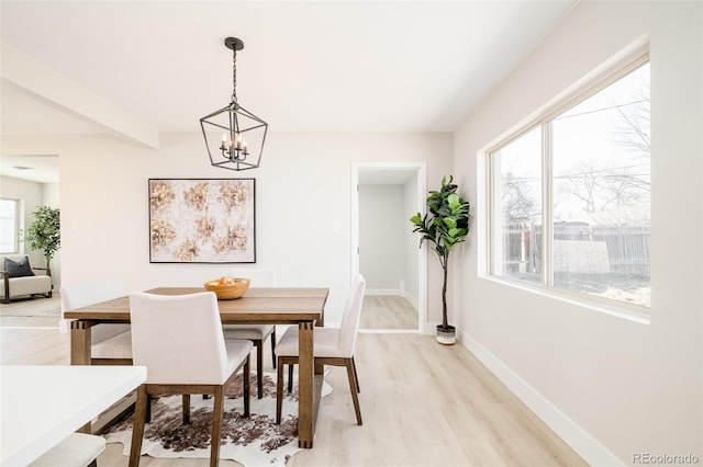 dining room featuring light wood-style floors, beamed ceiling, baseboards, and an inviting chandelier