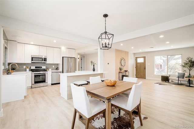 dining area featuring baseboards, a chandelier, light wood-style flooring, and recessed lighting