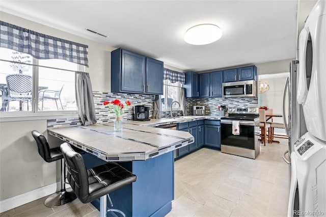 kitchen featuring blue cabinets, a breakfast bar, kitchen peninsula, and appliances with stainless steel finishes