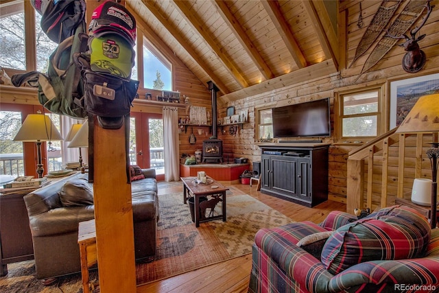 living room with beamed ceiling, a wood stove, wood ceiling, and wooden walls