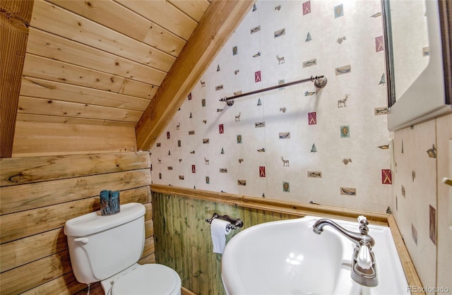 bathroom with sink, wooden ceiling, beamed ceiling, wood walls, and toilet