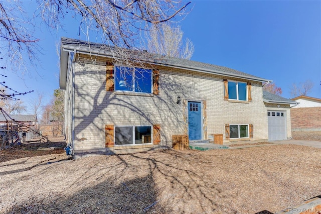 back of house with a garage, driveway, and brick siding