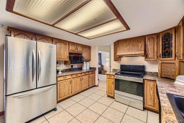 6708 W Portland Ave, Littleton, CO 80128 - kitchen with appliances with stainless steel finishes, light tile patterned floors, brown cabinets, and a sink