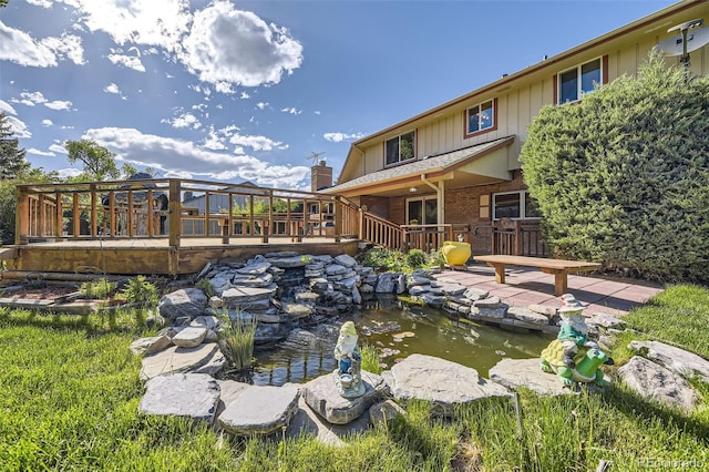 6708 W Portland Ave, Littleton, CO 80128 - back of property featuring a small pond, a deck, board and batten siding, and brick siding