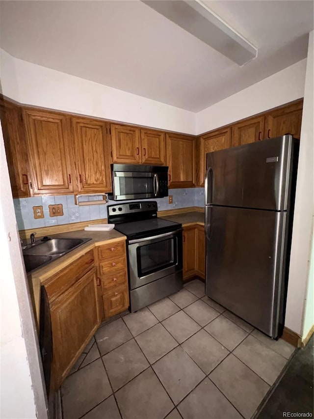 31270 John Wallace Rd Unit 306, Evergreen, CO 80439 - kitchen featuring appliances with stainless steel finishes, brown cabinets, light tile patterned floors, and backsplash