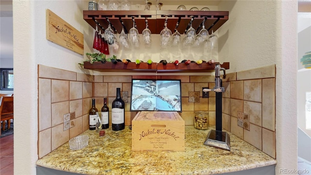 bar featuring light stone counters and backsplash