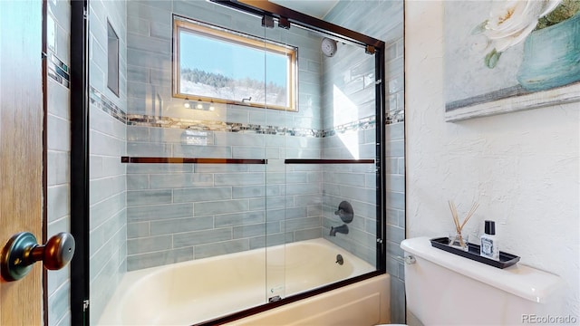 bathroom featuring shower / bath combination with glass door and toilet