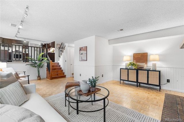 229 Berthoud Way, Golden, CO 80401 - living room with wainscoting, a textured ceiling, stairs, and rail lighting