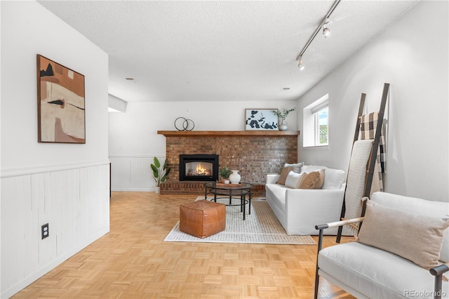 229 Berthoud Way, Golden, CO 80401 - living room featuring a textured ceiling, wainscoting, rail lighting, and a brick fireplace
