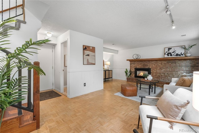 229 Berthoud Way, Golden, CO 80401 - living area featuring a textured ceiling, wainscoting, a brick fireplace, and track lighting