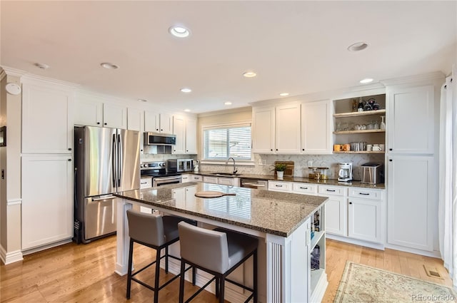 702 Windmill Pl, Highlands Ranch, CO 80126 - kitchen with stainless steel appliances, open shelves, white cabinets, light wood-style flooring, and recessed lighting