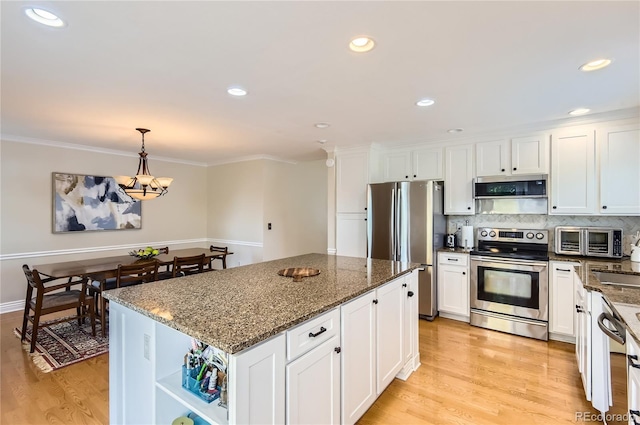 702 Windmill Pl, Highlands Ranch, CO 80126 - kitchen with stainless steel appliances, light wood-type flooring, white cabinets, crown molding, and recessed lighting