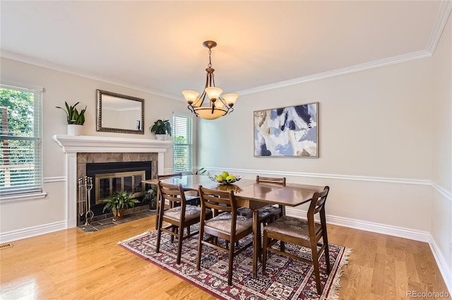 702 Windmill Pl, Highlands Ranch, CO 80126 - dining space featuring a tiled fireplace, a chandelier, light wood finished floors, and crown molding