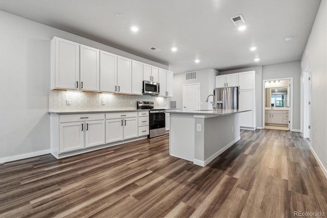 kitchen with stainless steel appliances, visible vents, and decorative backsplash