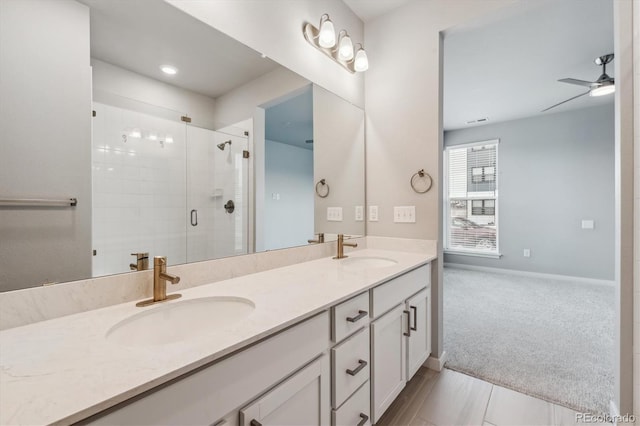 full bathroom with double vanity, a sink, a ceiling fan, and a shower stall