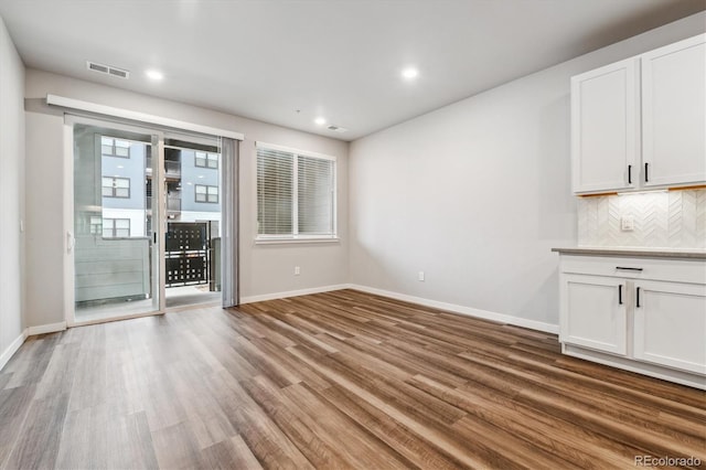 unfurnished dining area featuring baseboards, visible vents, and wood finished floors