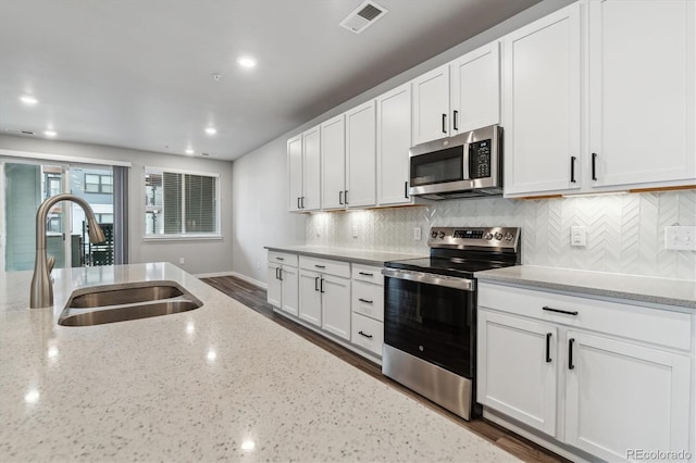 kitchen featuring stainless steel appliances, white cabinets, visible vents, and a sink