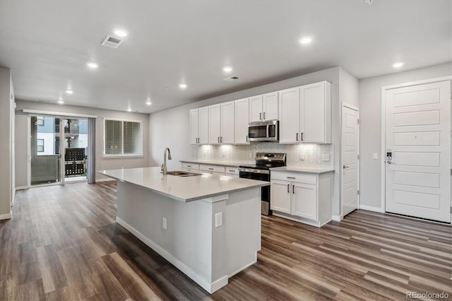 kitchen with a sink, visible vents, white cabinetry, appliances with stainless steel finishes, and a center island with sink